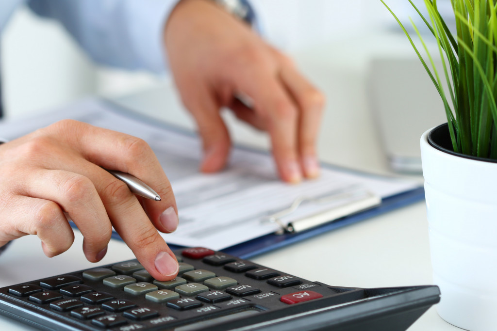 a man using a calculator and checking balance sheet