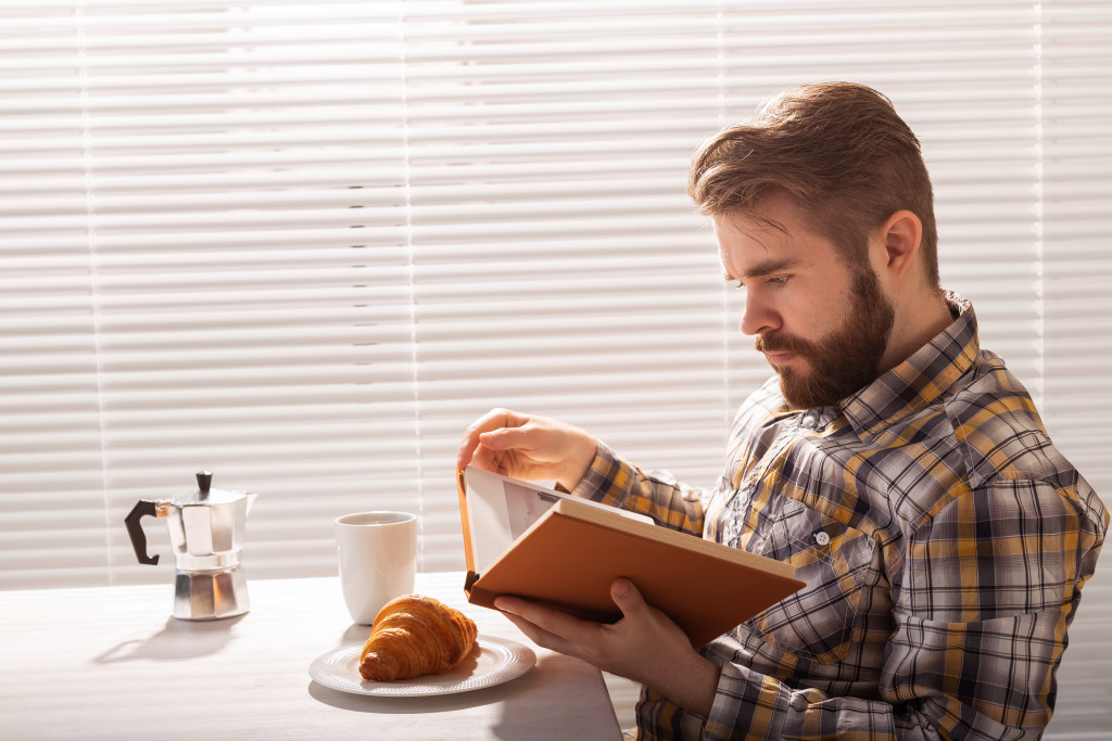 A man seriously reading a hardbound book in a cafe