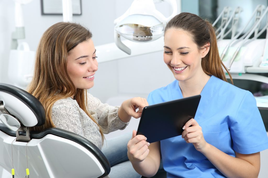 Dentist and patient choosing treatment in a consultation with medical equipment in the background