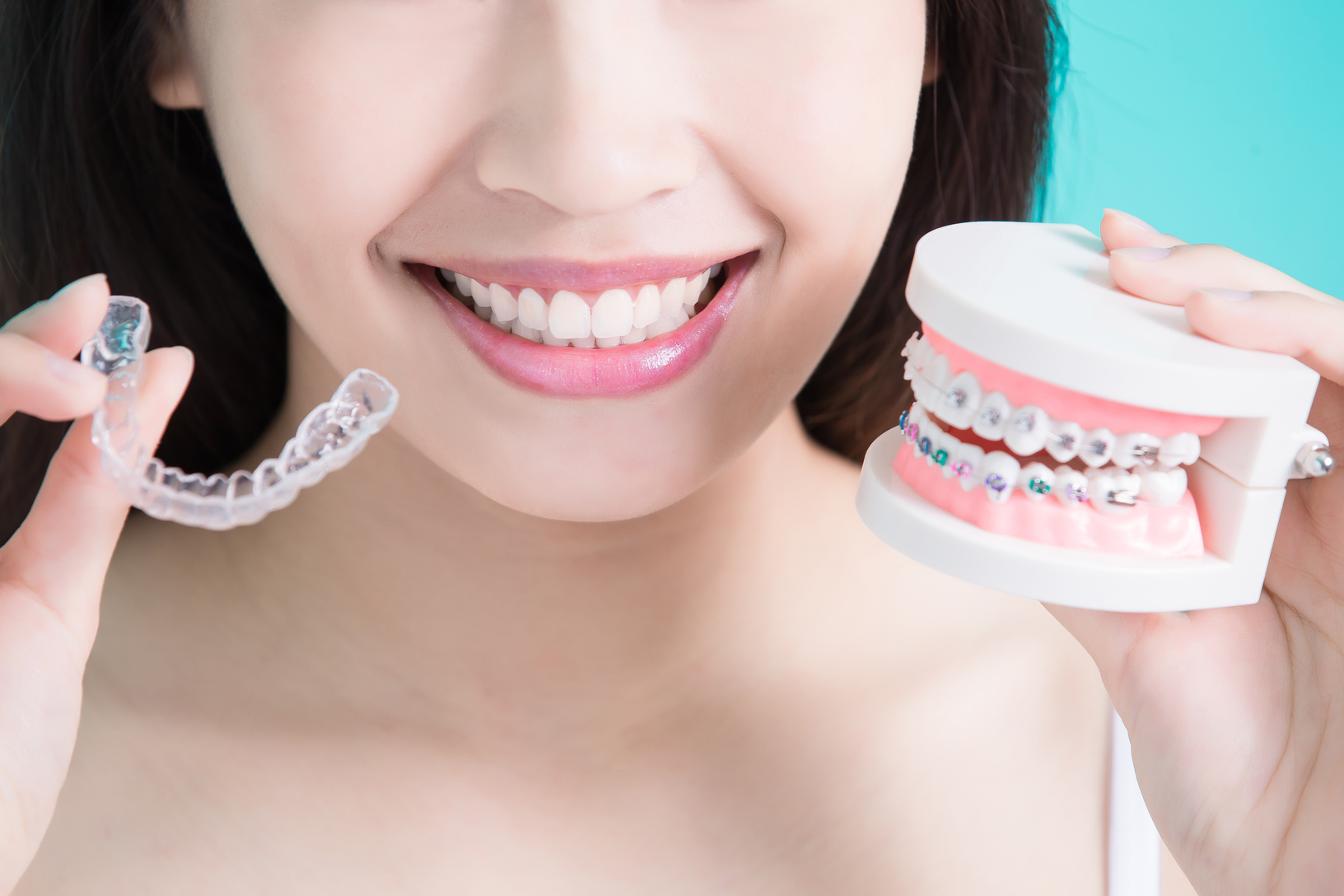 Woman holding an invisible braces and a denture