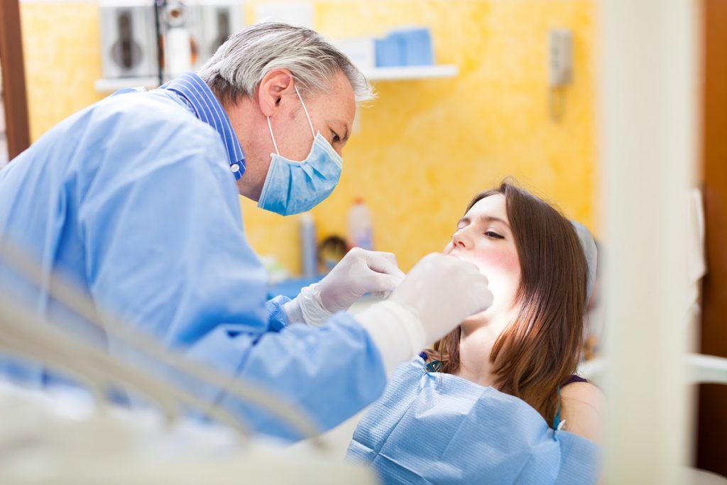 woman is sedated while dentist is checking her mouth