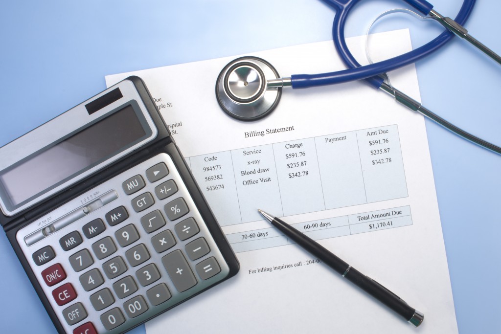Medical Billing Statement Under A Calculator, A Pen and A Stethoscope