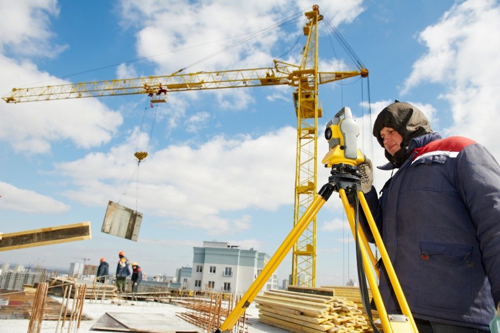 man surveying land next to crane