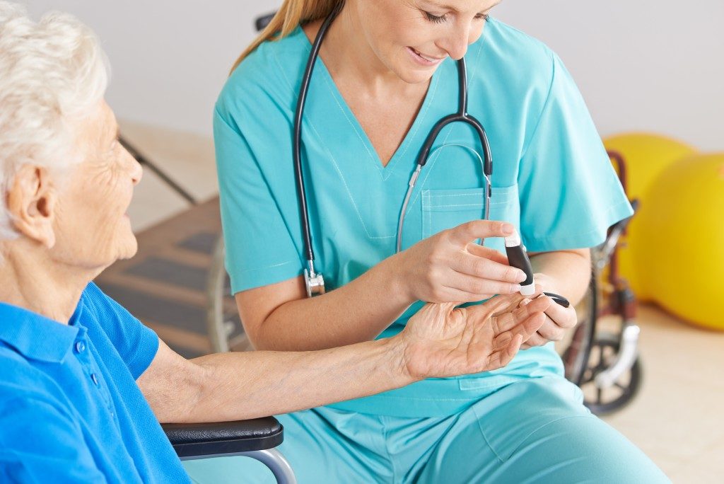 Female nurse monitoring the senior's blood sugar