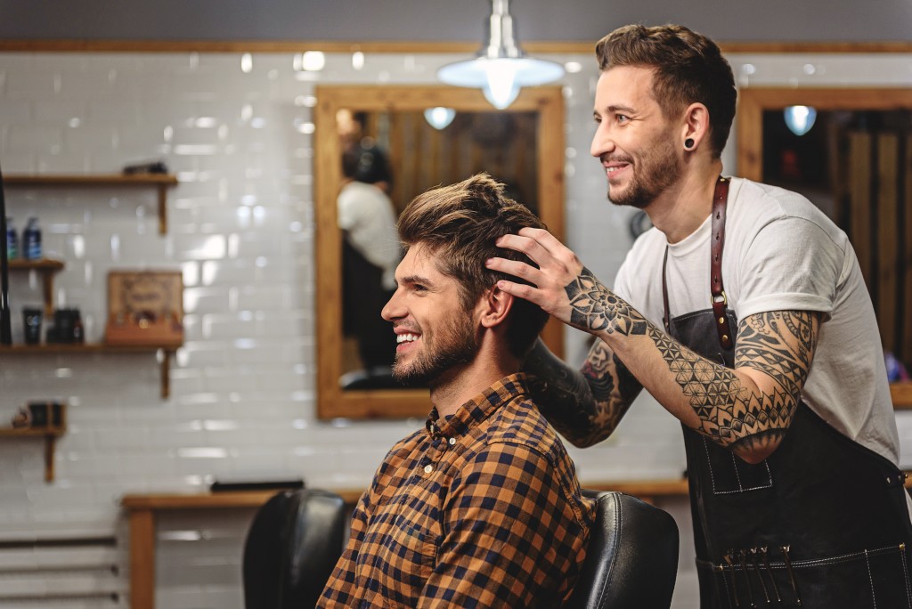 barber styling hair of handsome guy