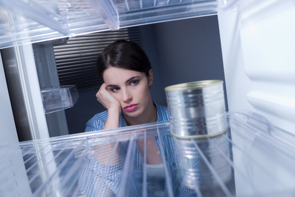 sad woman looking at empty freezer