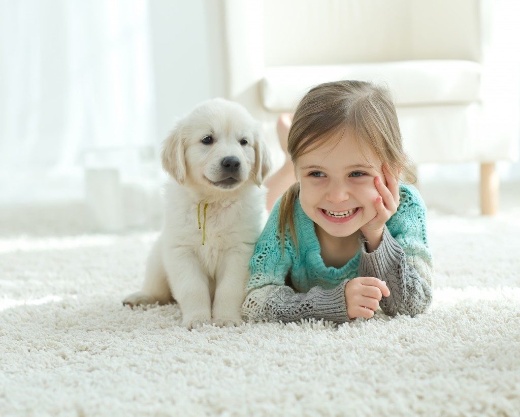 child with the dog lying on the mat at home