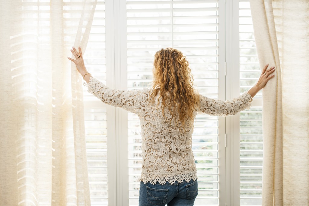 woman parting window curtains