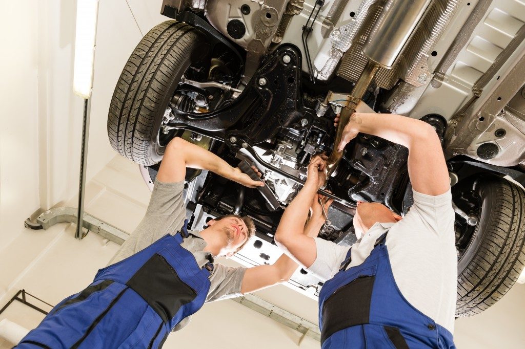 workers in auto repair shop fixing a car