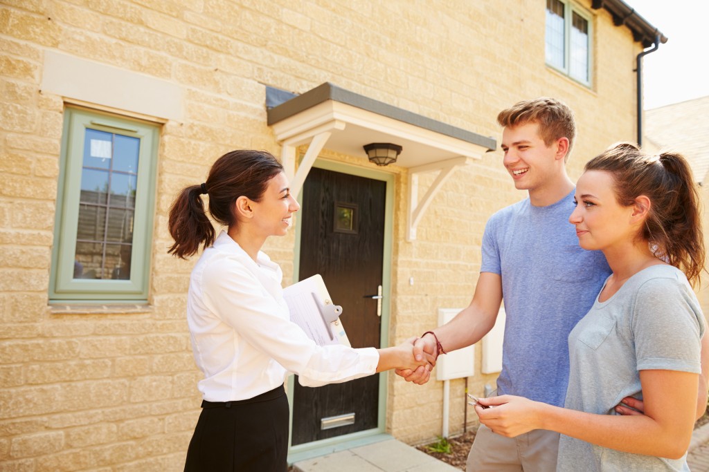 young home buyers handshaking real estate agent