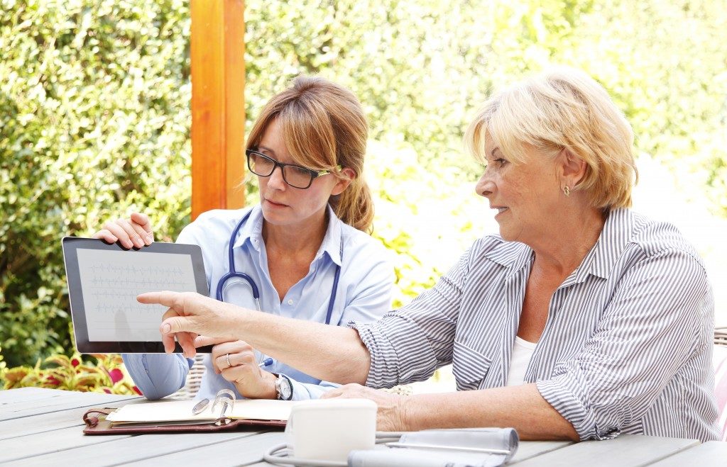 Doctor helping elderly use an Ipad