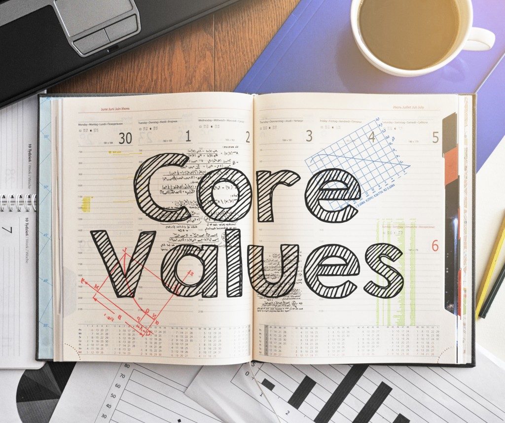 Notebook with text inside Core Values on table with coffee