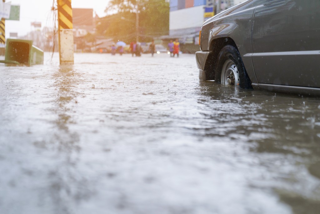 flood water - people walking in the rain on flooded road