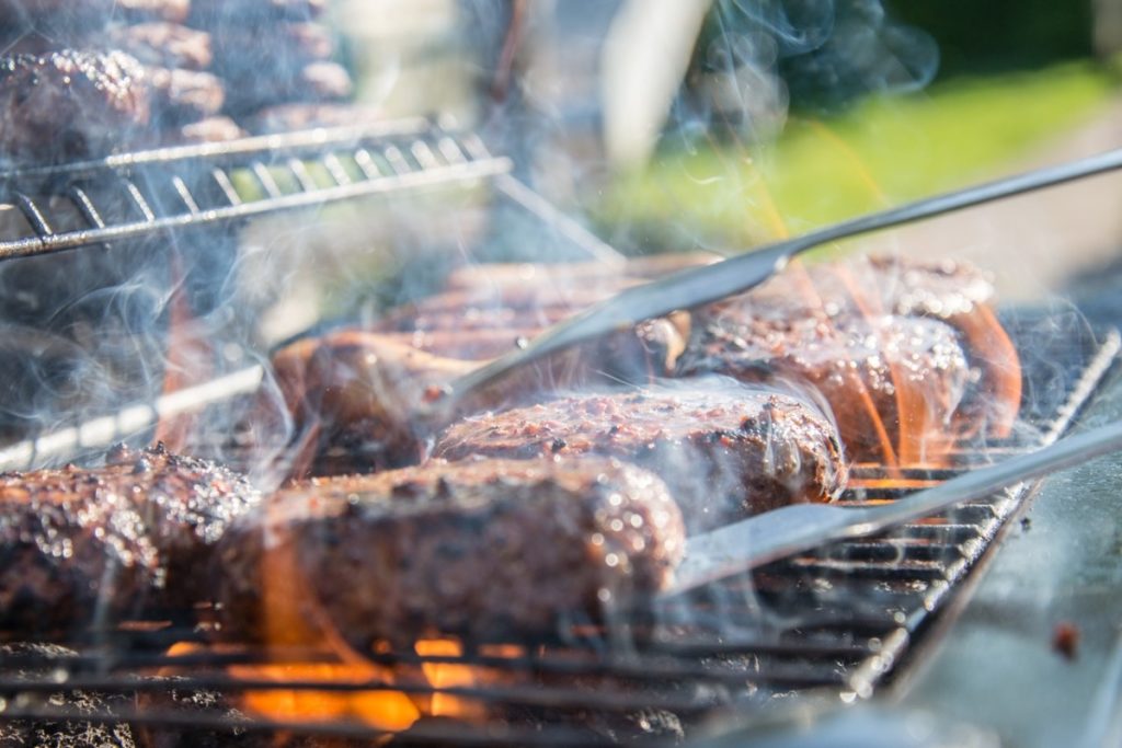 person grilling burger patties