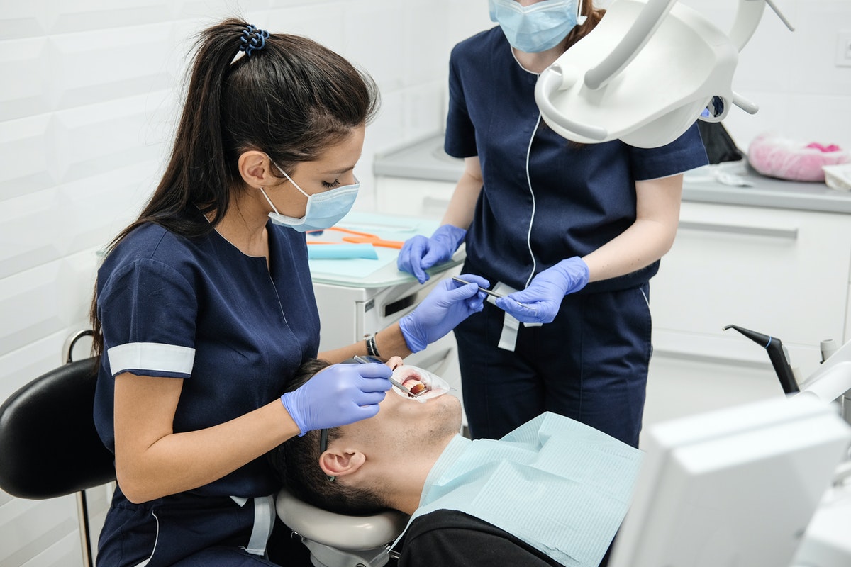 dentist operating on her patient with assistance