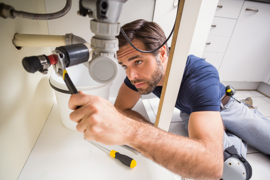 A professional plumber inspecting and fixing a sink