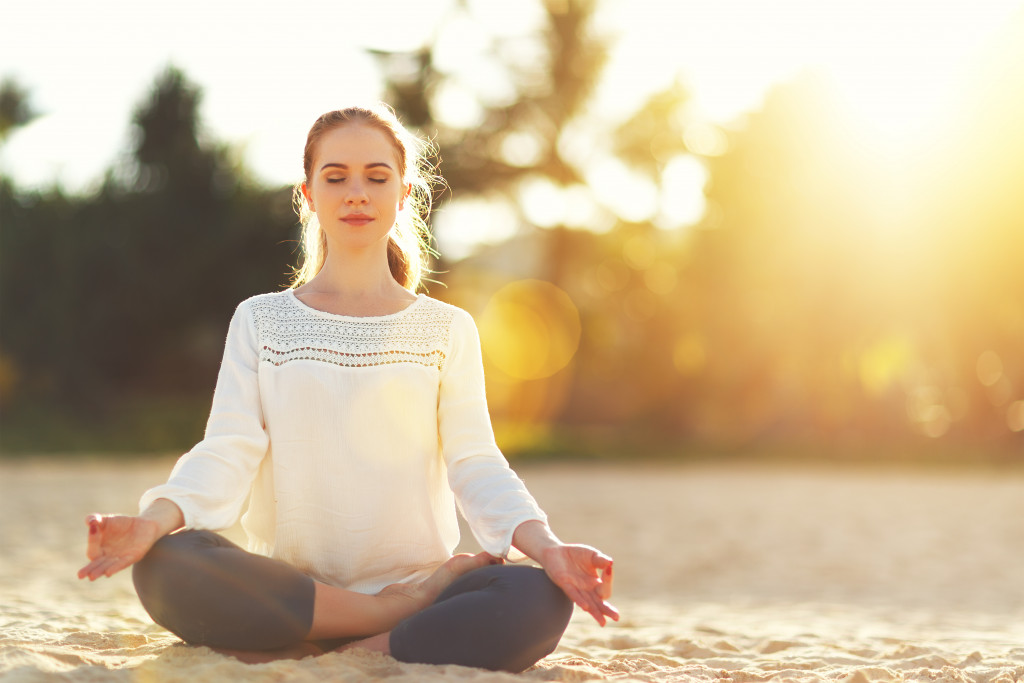 woman in ponytails meditating outdoors at sunrise