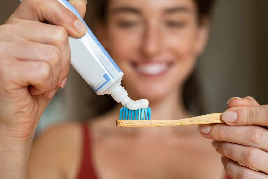 young woman putting toothpaste on toothbrush