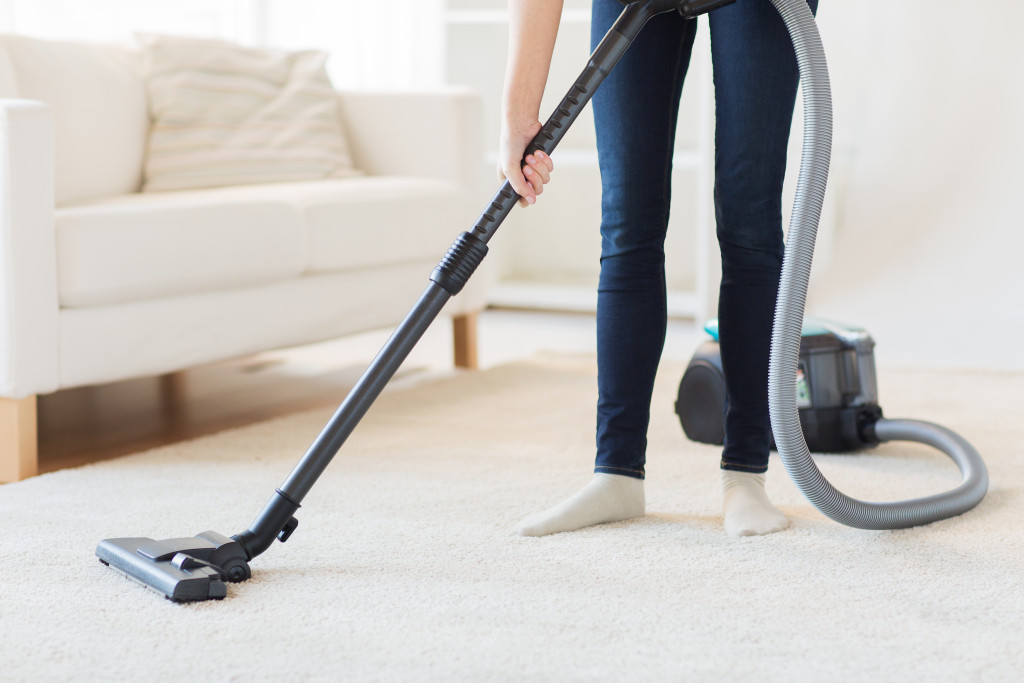 woman vacuuming carpet of home